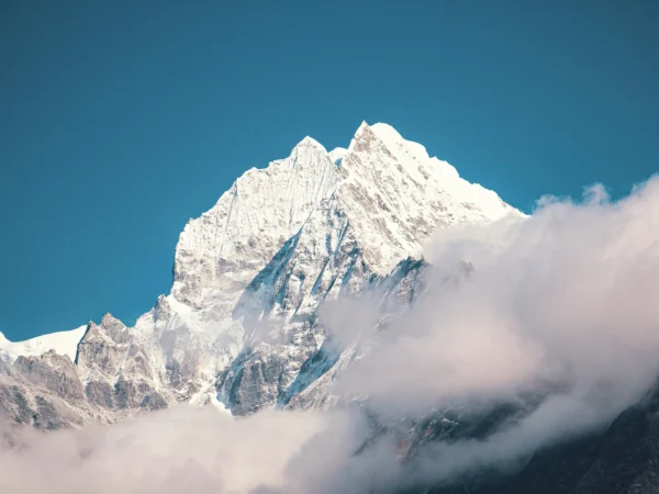 Majestic view of a snow-covered mountain peak enveloped in clouds, showcasing natural beauty and tranquility